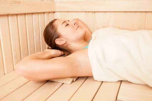 Retrato de mujer morena cubierta de toalla tumbada en la sauna —  Fotos de Stock