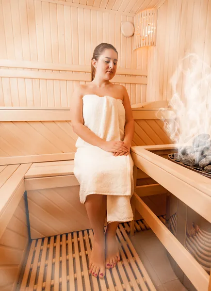 Mujer en toalla relajante en sauna finlandesa al vapor — Foto de Stock