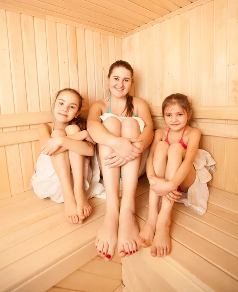 Two little girls relaxing in sauna with mother — Stock Photo, Image