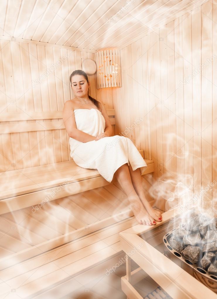Woman in steamed finnish sauna sitting with closed eyes