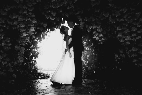 Black and white photo of bride and groom dancing at tree tunnel