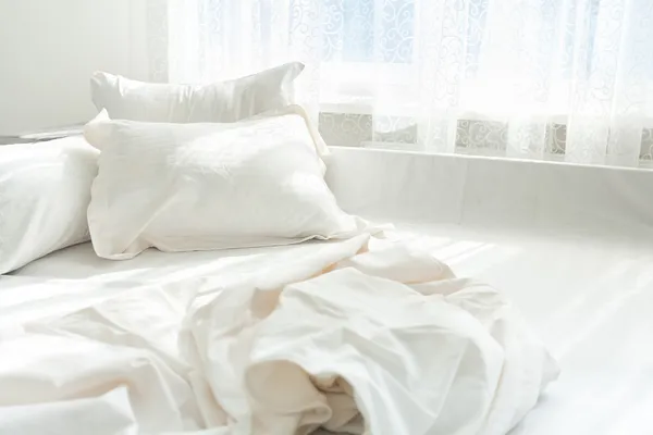 Foto de cama desordenada contra ventana —  Fotos de Stock