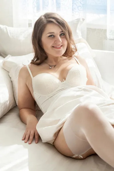 Photo of brunette girl in lingerie lying in bed at morning — Stock Photo, Image