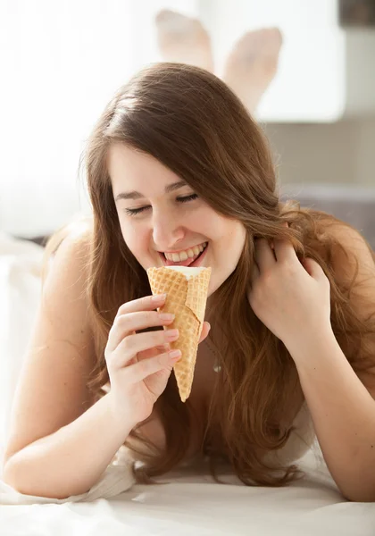 Bruna donna mangiare gelato in camera da letto — Foto Stock