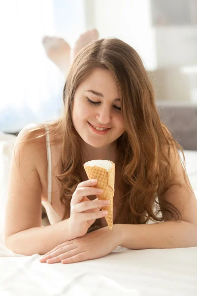 Dívka ležela na posteli a při pohledu na kužel zmrzliny — Stock fotografie