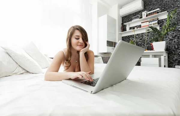 Woman working at home with laptop in bed — Stock Photo, Image