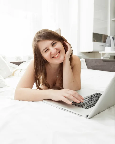 Portret van schattige lachende vrouw liggen in bed met laptop — Stockfoto