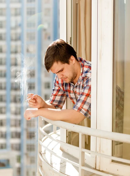 Uomo depresso fumare sigaretta fuori dalla finestra — Foto Stock