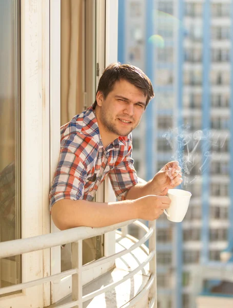 Portrait of hipster guy drinking coffee on balcony — Stock Photo, Image