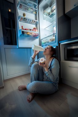 donna seduta sul pavimento in cucina e a fine cenamutfak katında oturan ve geç akşam yemeği kadın