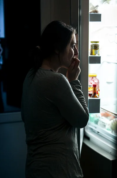 Mujer en pijama abriendo refrigerador por la noche — Foto de Stock