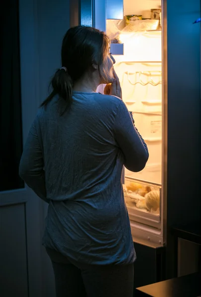 Junge Frau schaut spät in der Nacht in den Kühlschrank — Stockfoto