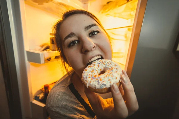 Mulher com fome comer donut na cozinha — Fotografia de Stock