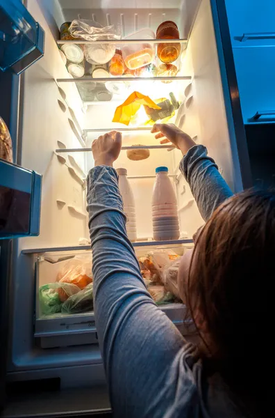 Wanita dalam piyama mencapai donat di atas rak lemari es — Stok Foto