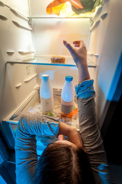 Mulher tomando donut da prateleira superior do refrigerador — Fotografia de Stock