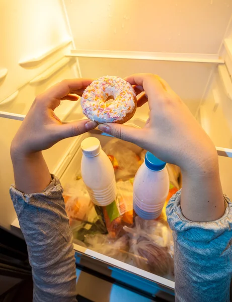 Hands taking big donut from top shelf of fridge — Stock Photo, Image
