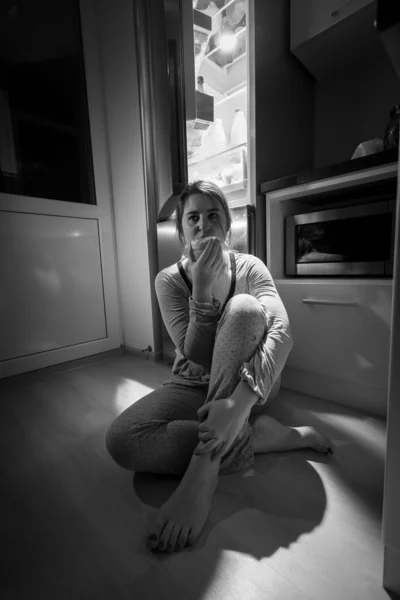 Photo of woman sitting next to fridge at night — Stock Photo, Image