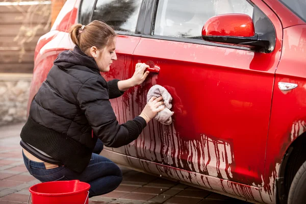 Женщина убирает дверь машины от грязи и грязи — стоковое фото