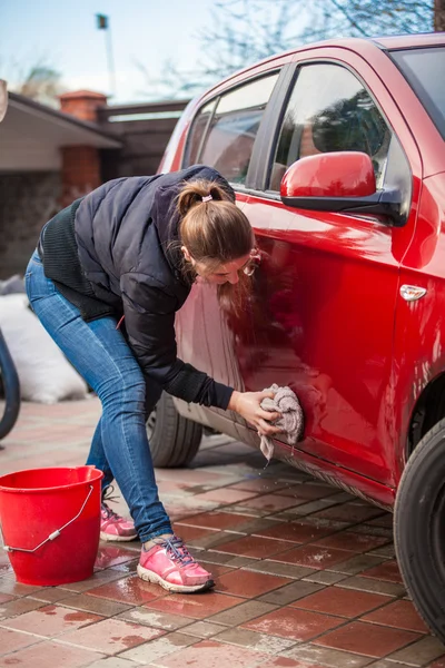 Slim woman washing red car door with rug — Stock Photo, Image