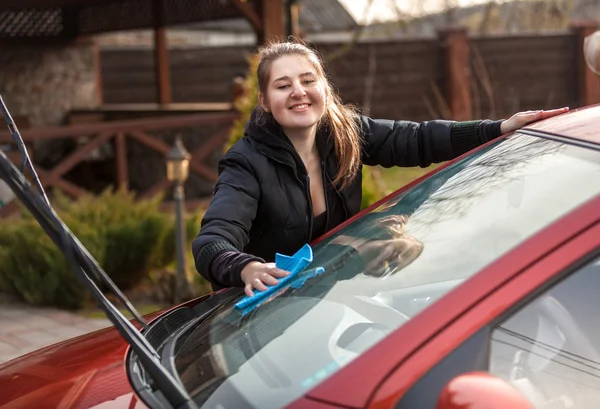 Mujer sonriente lavando parabrisas de coche en el patio — Foto de Stock
