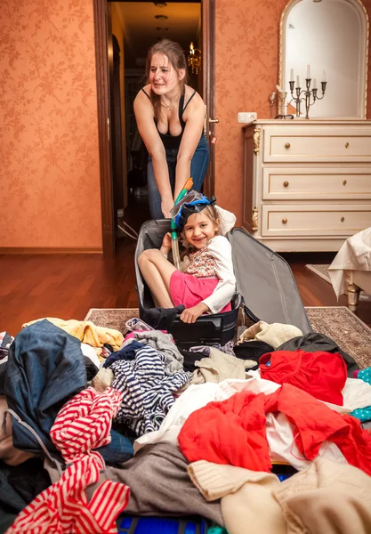 Mulher carregando grande mala com menina sentada dentro — Fotografia de Stock