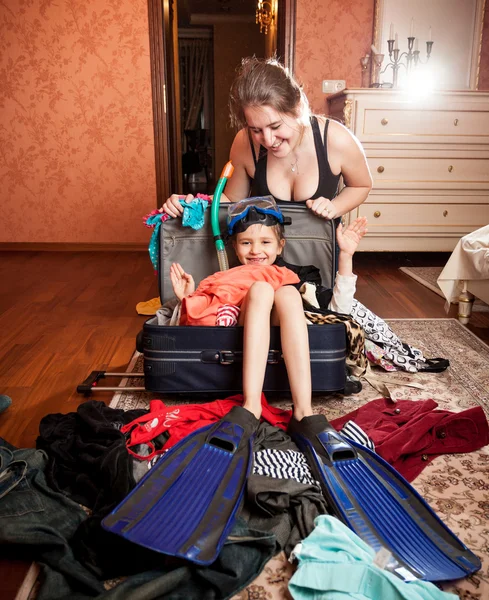 Mamma förpackning dotter i mask och snorkel i resväska — Stockfoto