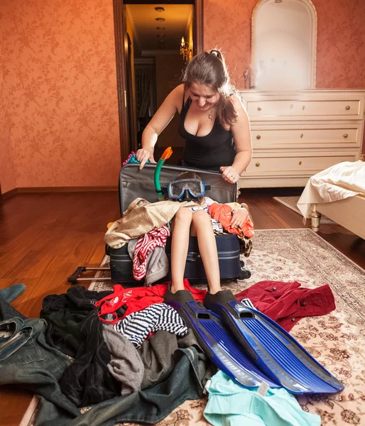 Женщина упаковывает девушку в большой чемодан — стоковое фото