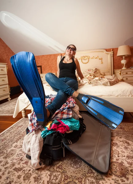 Woman in flippers holding legs on suitcase at bedroom — Stock Photo, Image