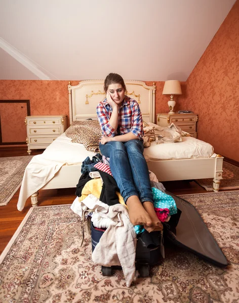 Depressed woman sitting on unpacked suitcase — Stock Photo, Image