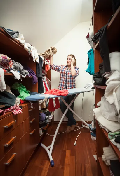 Ama de casa mirando ropa no planchada en el armario —  Fotos de Stock