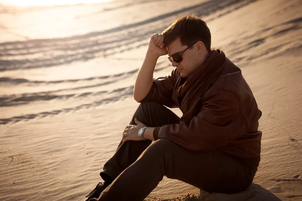 Όμορφος άνδρας κάθεται και σκέψης σχετικά με άμμο αμμόλοφος — Φωτογραφία Αρχείου