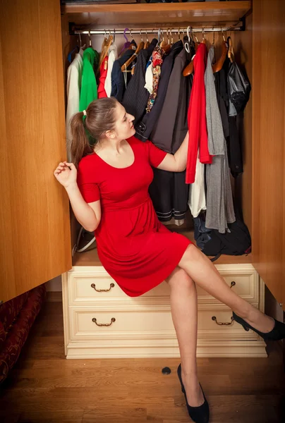 Mulher morena escolhendo vestidos em grande guarda-roupa — Fotografia de Stock