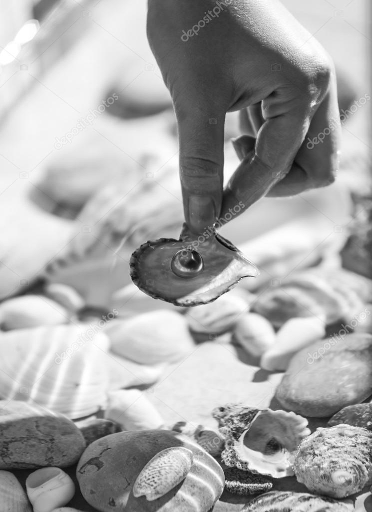 Photo of female hand holding pearl on seashell