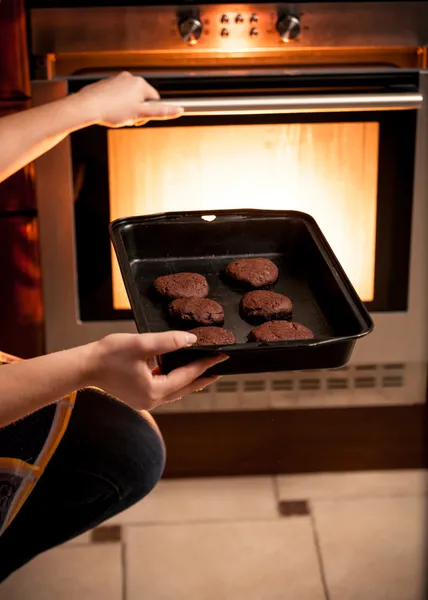 Фото домохозяйки, кладущей сковородку с печеньем в духовку — стоковое фото