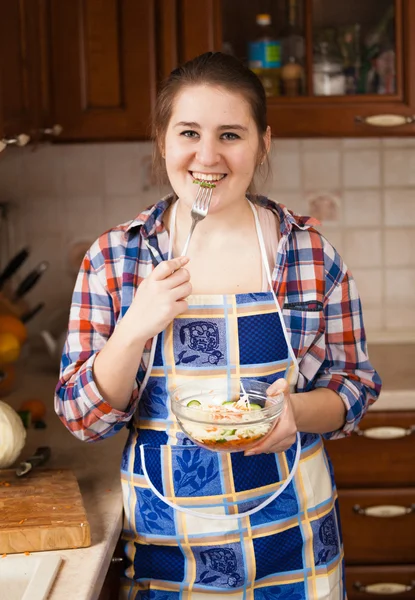 Lächelnde Hausfrau isst Salat in der Küche — Stockfoto