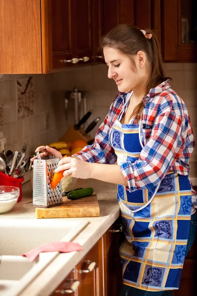 Młoda kobieta, kraty i marchew w kuchni — Zdjęcie stockowe