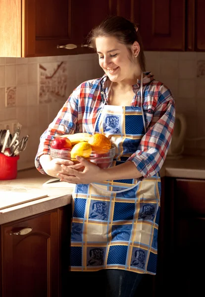 Žena nosí zástěru drží čerstvé mísa s ovocem — Stock fotografie