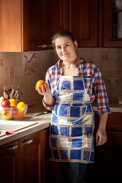 Sonriente ama de casa sosteniendo naranja — Foto de Stock