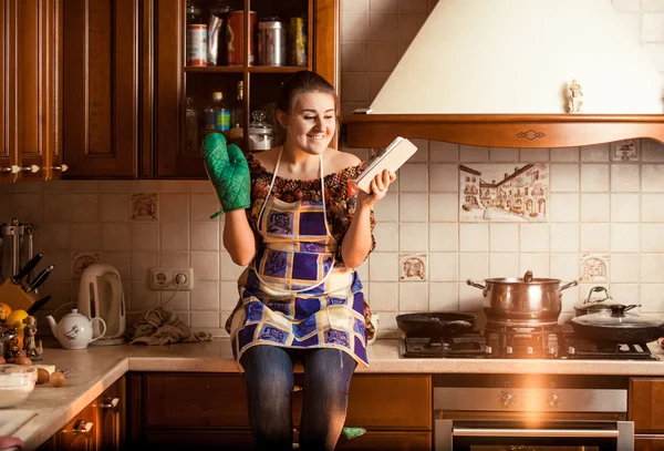 Potret ibu rumah tangga duduk di atas meja dan menggunakan tablet — Stok Foto