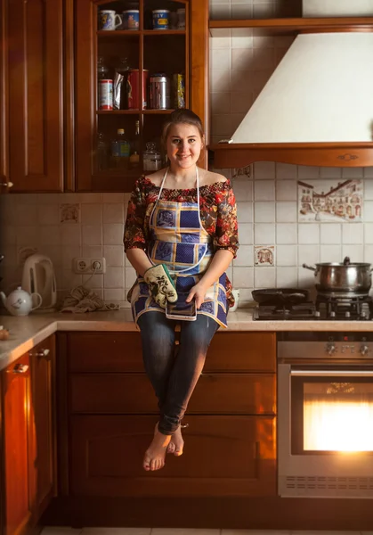Wanita duduk di atas meja saat memasak makan malam di oven — Stok Foto
