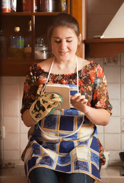 Potret ibu rumah tangga muda menggunakan tablet saat memasak — Stok Foto