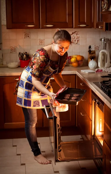 Mulher colocando biscoitos de chocolate no forno quente — Fotografia de Stock