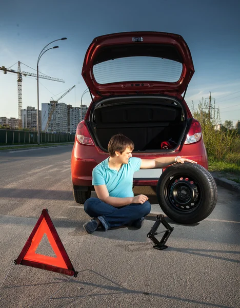 Muž sedí na silnici a opřel se o Pokažené auto — Stock fotografie