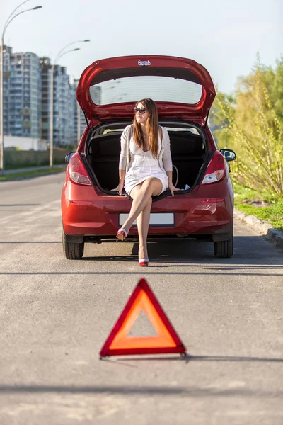 Mujer indefensa sentada cerca de coche rojo roto —  Fotos de Stock