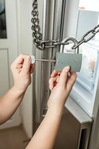 Photo of female opening lock with chain on refrigerator — Stock Photo, Image