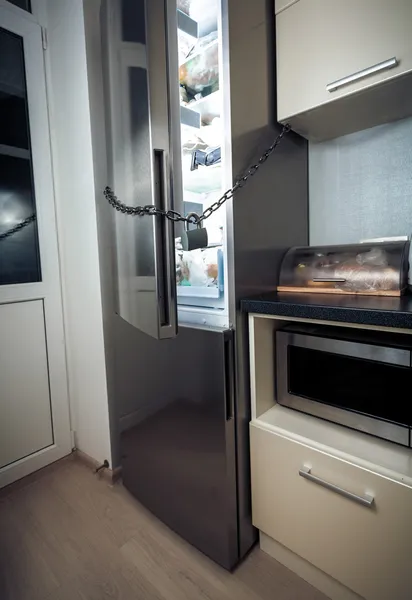 Холодильник на кухне заперт цепью — стоковое фото