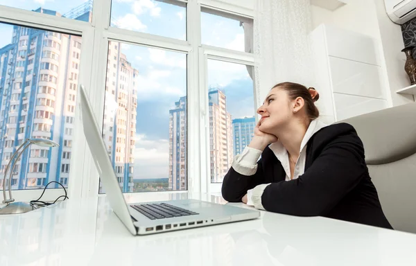 Бізнес-леді сидить за столом і дивиться з вікна — стокове фото