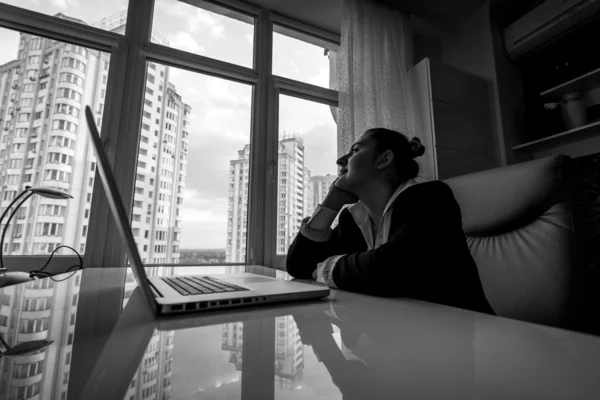 Мрійлива бізнес-леді дивиться з вікна в офісі — стокове фото