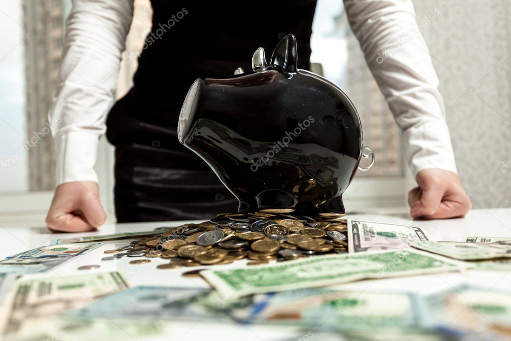 businesswoman standing behind piggy bank on pile of money