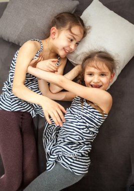 two young sisters pushing each other on bed